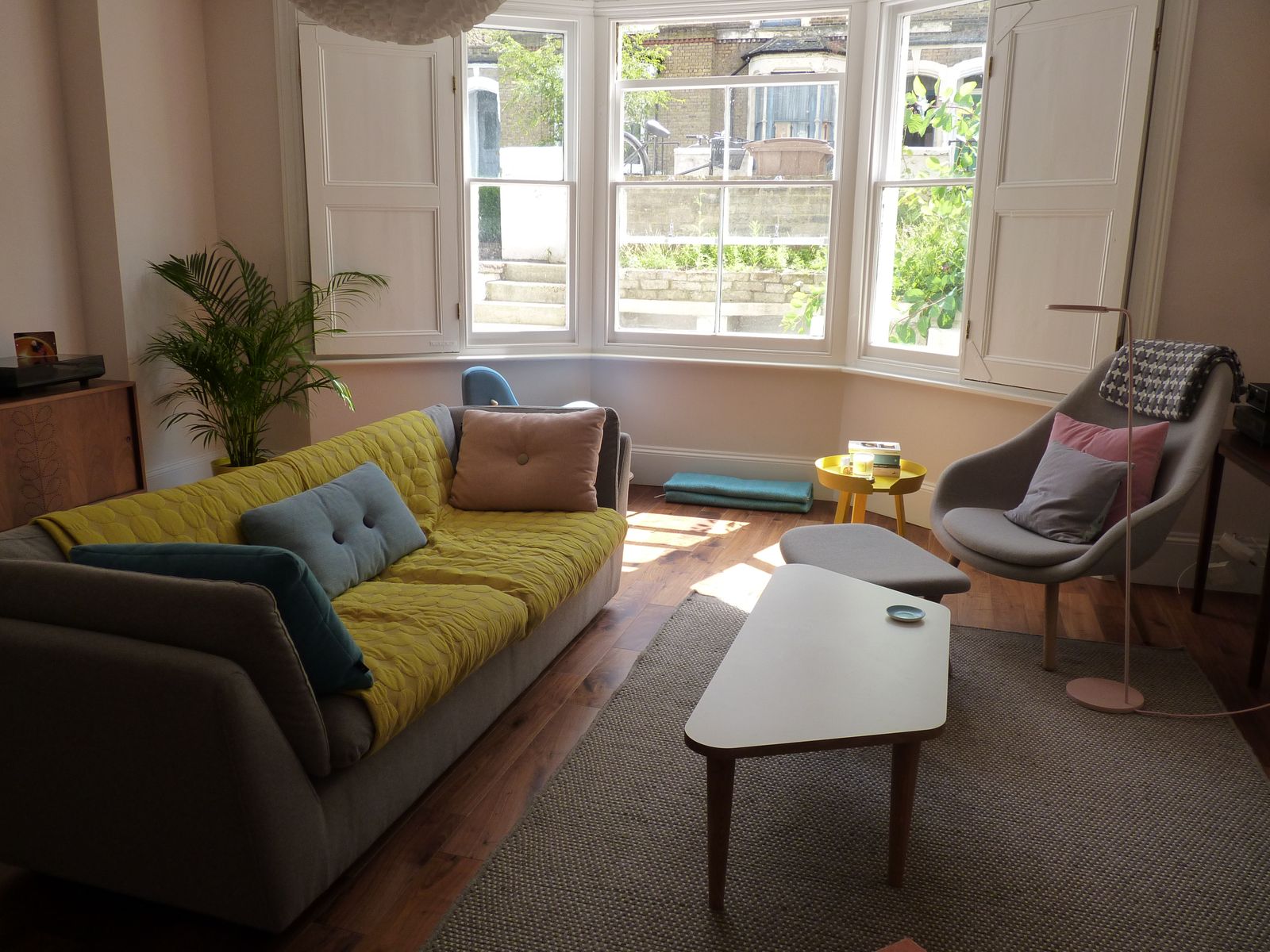 Bright, comfortable living room with a yellow sofa and a bay window