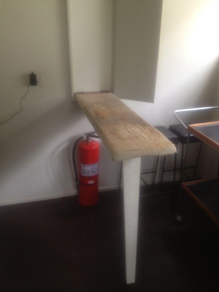 Red fire extinguisher kept ready beside a wooden table